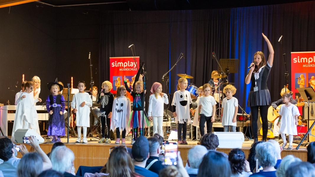 Kinder der musikalischen Früherziehung singen auf der Bühne in Kostümen.