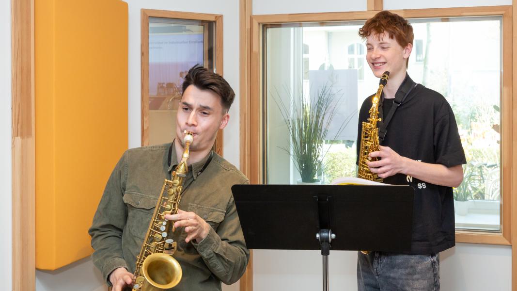 Saxophonlehrer spielt mit Schüler vor